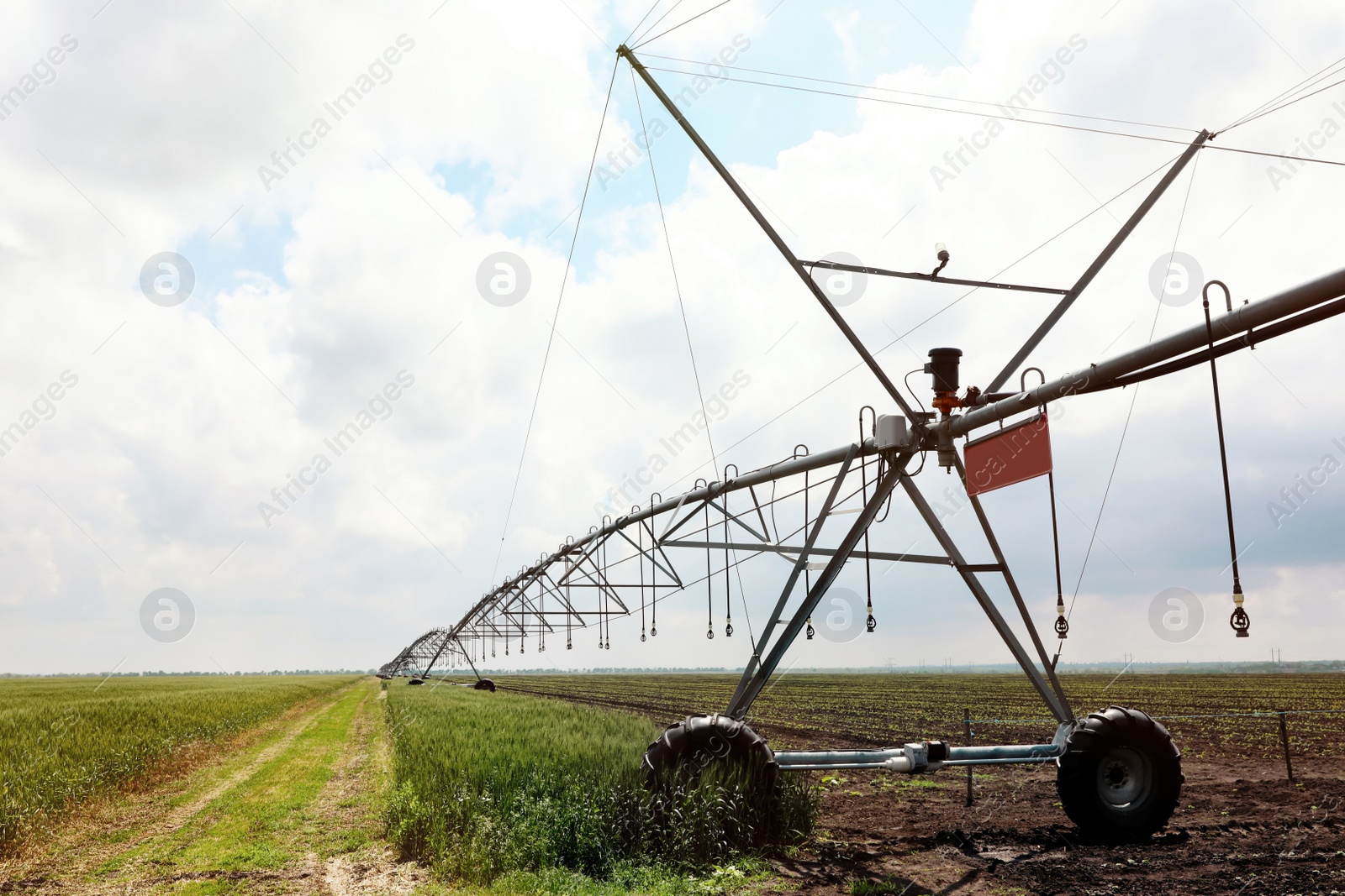 Photo of Modern irrigation system in field under cloudy sky. Agricultural equipment