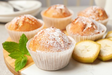 Photo of Tasty muffins served with mint and banana on board, closeup
