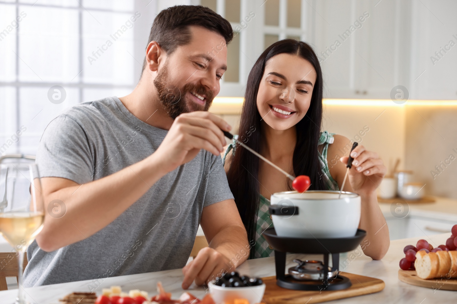 Photo of Affectionate couple enjoying fondue during romantic date in kitchen