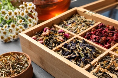 Photo of Different dry teas and chamomile flowers on table, closeup