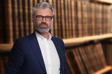 Image of Confident lawyer near shelves with books, space for text