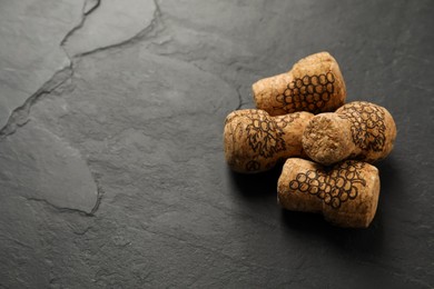 Photo of Sparkling wine corks with grape images on black table. Space for text