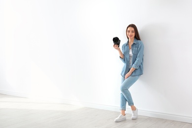 Female photographer with camera near light wall indoors