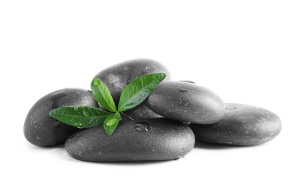 Photo of Spa stones and green leaves with water drops on white background