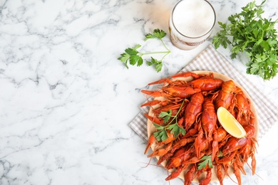 Photo of Delicious boiled crayfishes on white marble table, flat lay. Space for text