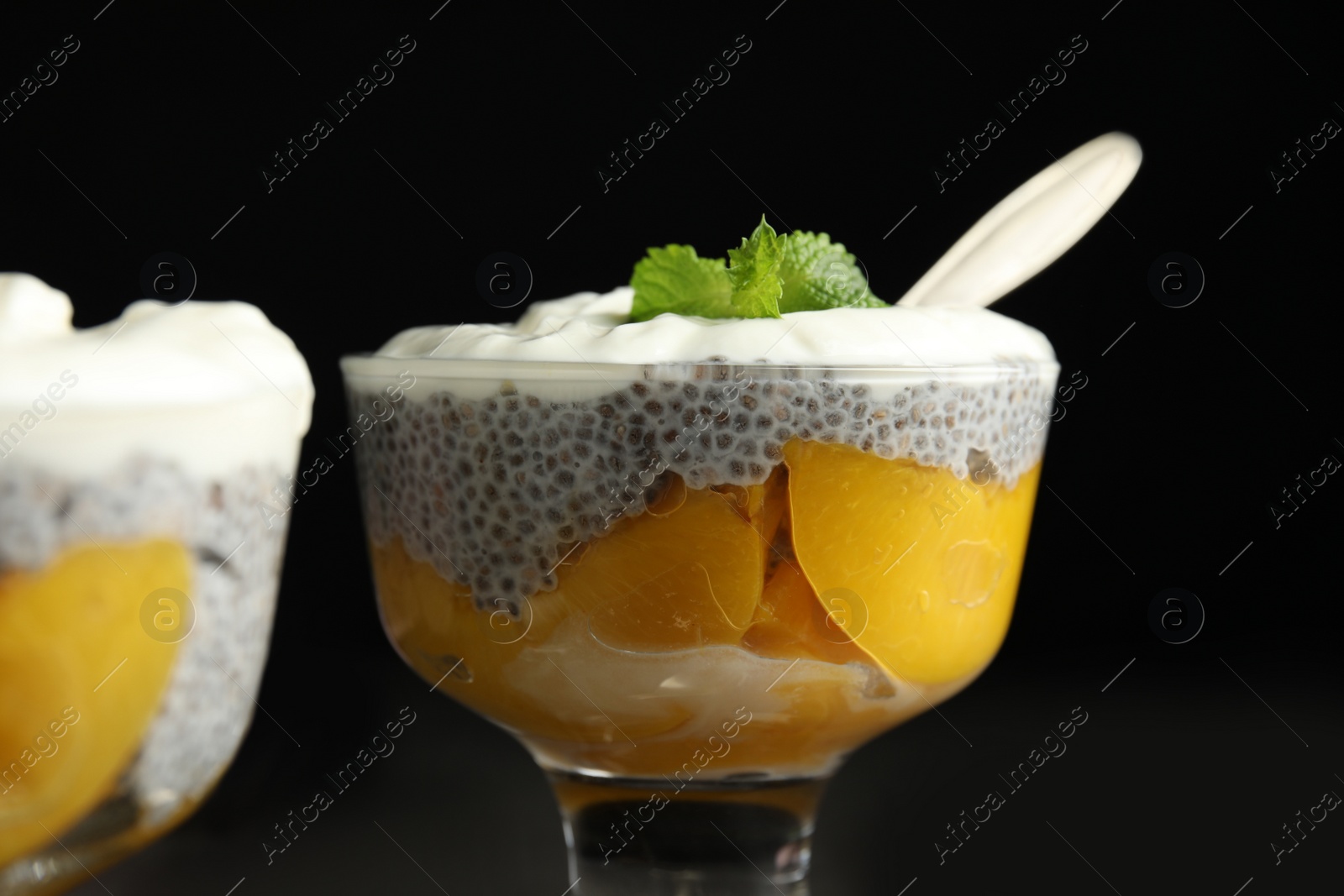 Photo of Tasty peach dessert with yogurt and chia seeds on black background, closeup