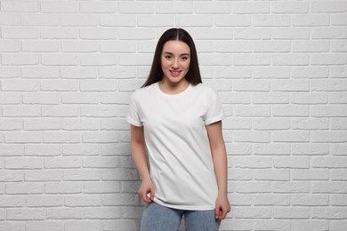 Woman wearing stylish T-shirt near white brick wall