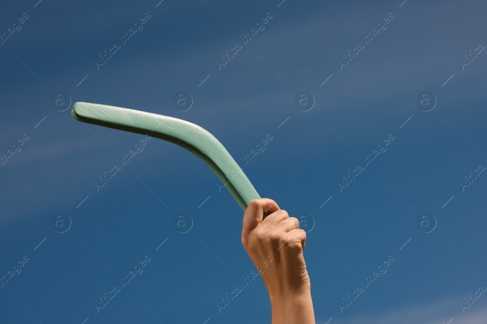 Photo of Woman throwing boomerang against blue sky, closeup. Space for text