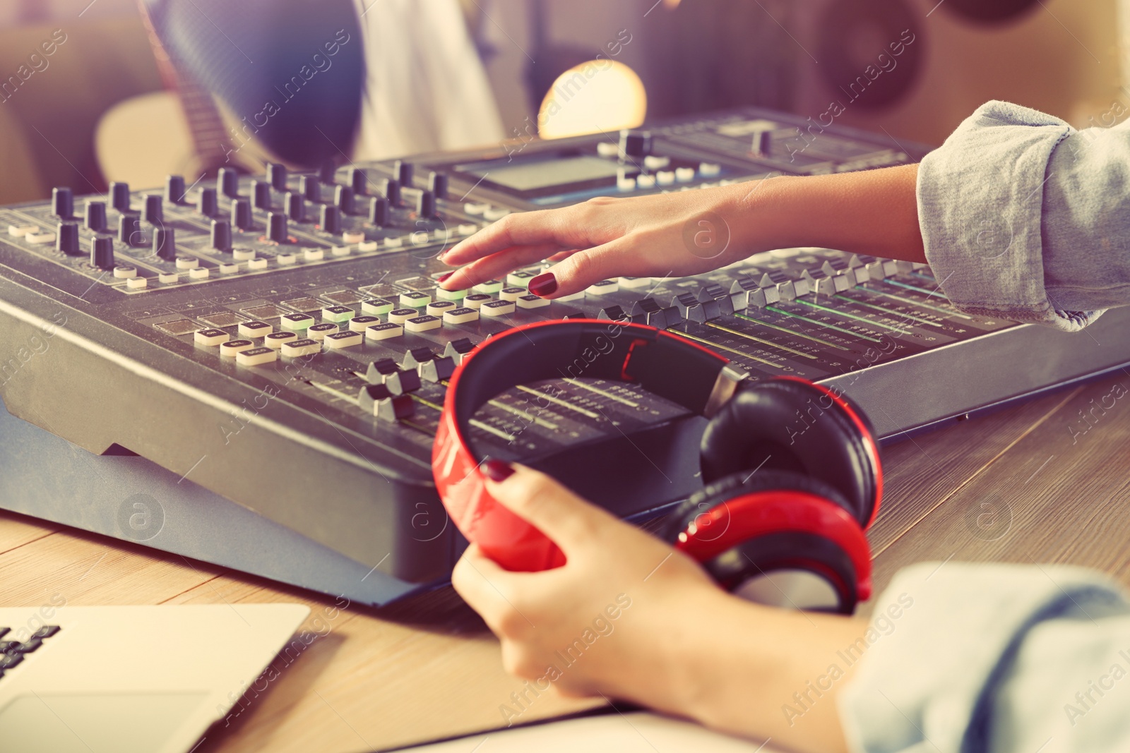 Photo of Woman working with professional mixing console in modern radio studio, closeup