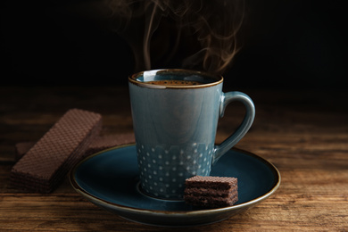 Photo of Delicious wafer and coffee on wooden table