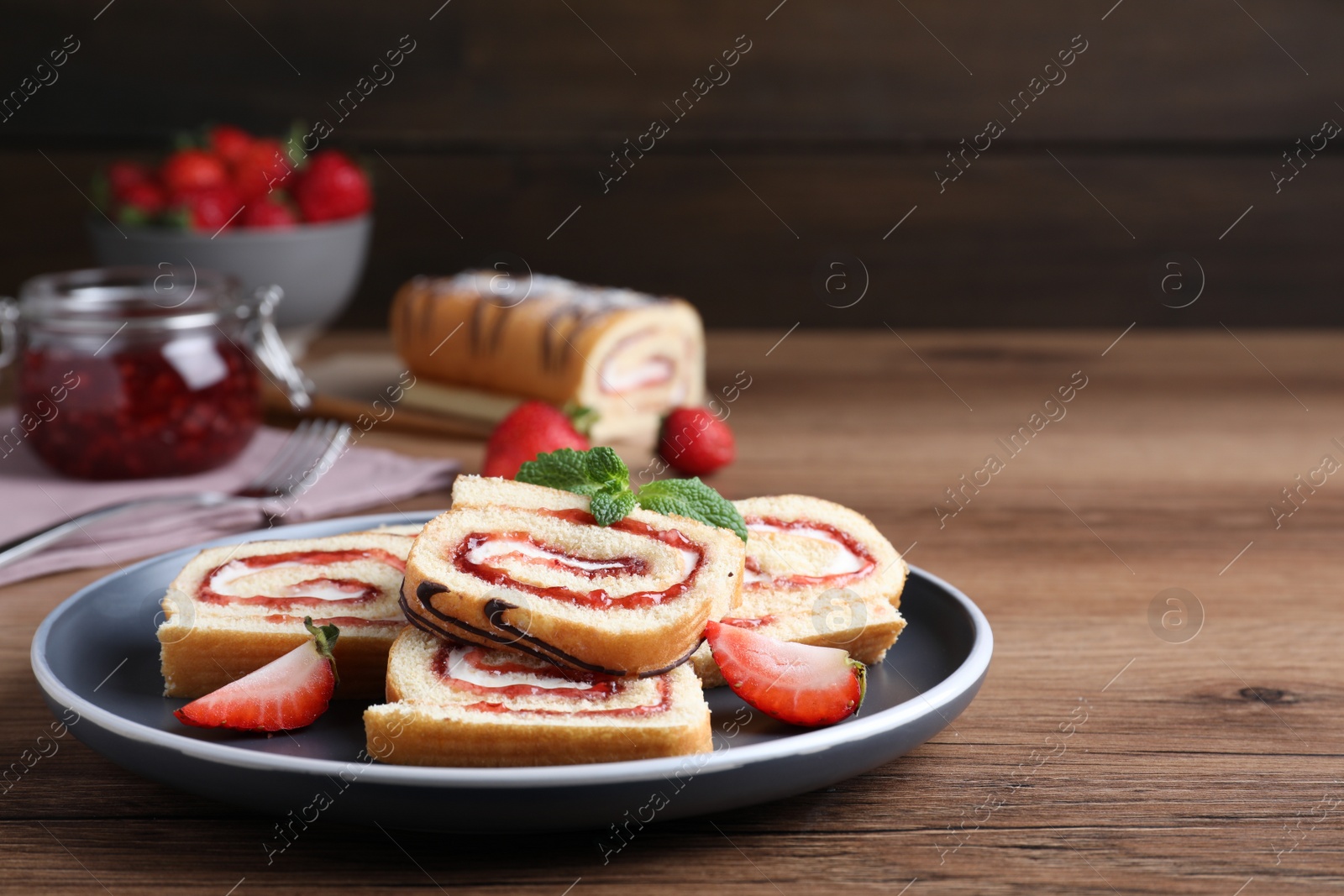 Photo of Tasty cake roll with strawberry jam and cream on wooden table
