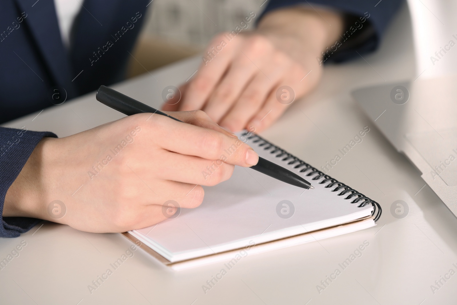 Photo of Woman writing in notebook at white table, closeup