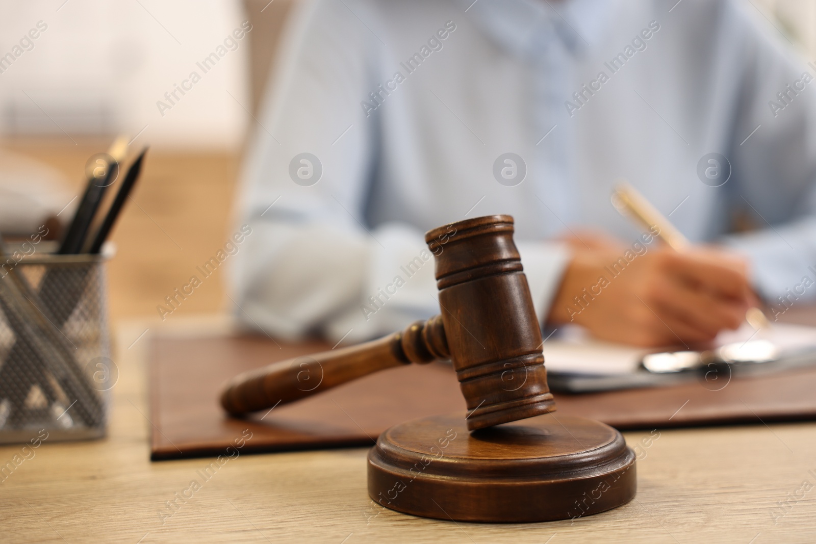 Photo of Notary with clipboard writing notes at workplace in office, focus on mallet