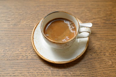 Photo of Cup of aromatic coffee on wooden table, above view