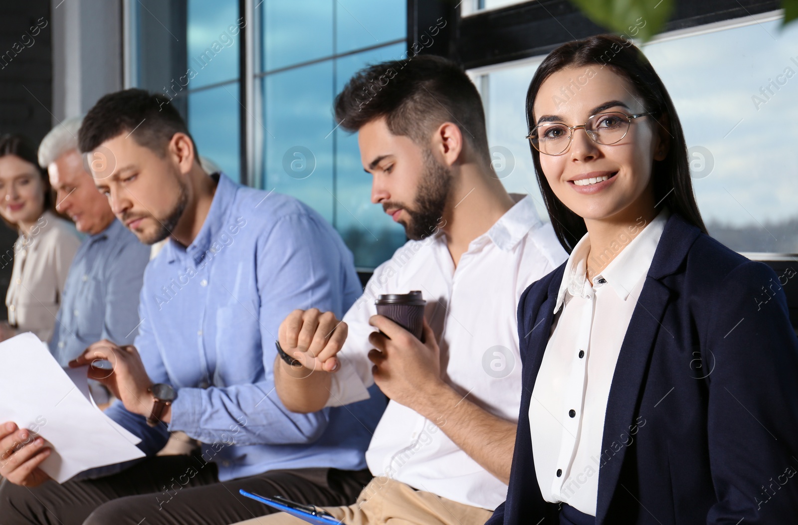 Photo of Young woman with eyeglasses waiting for job interview in office hall