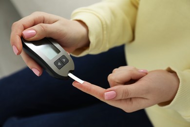 Photo of Diabetes. Woman checking blood sugar level with glucometer at home, closeup