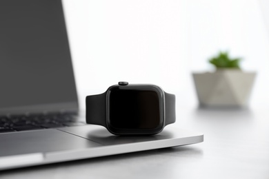 Photo of Stylish smart watch and laptop on grey table, closeup
