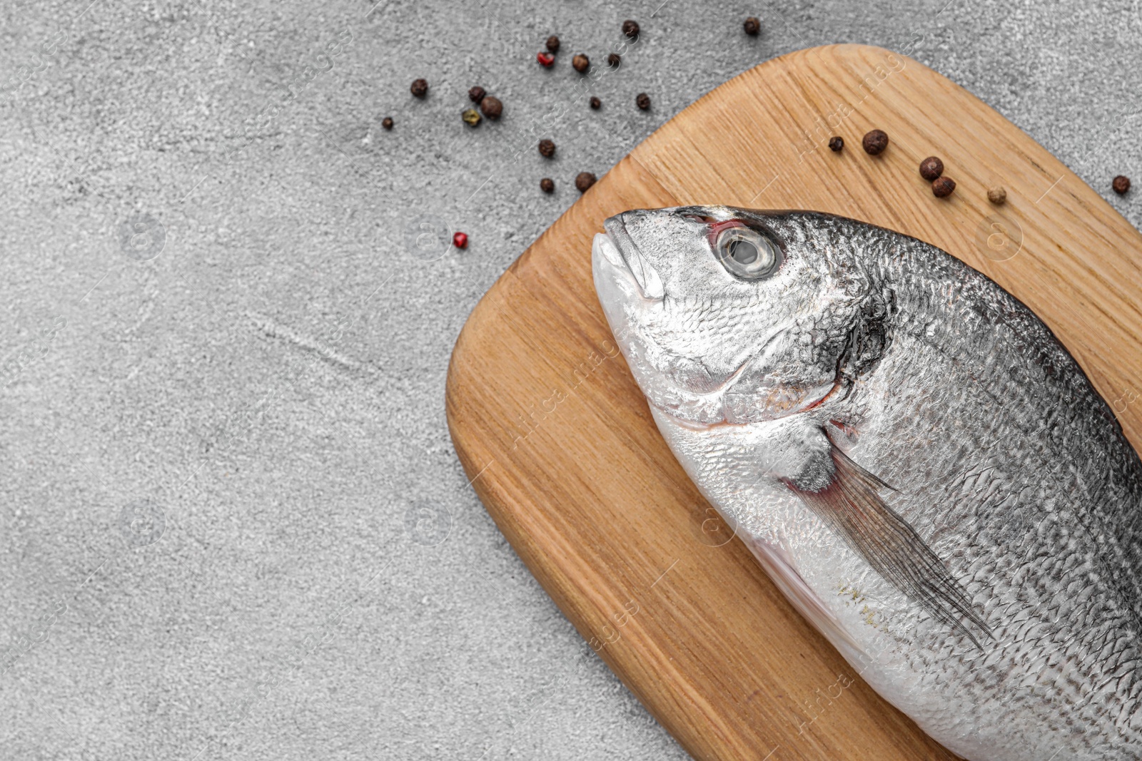 Photo of Fresh dorado fish and peppercorns on light gray table, flat lay. Space for text