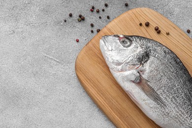 Photo of Fresh dorado fish and peppercorns on light gray table, flat lay. Space for text