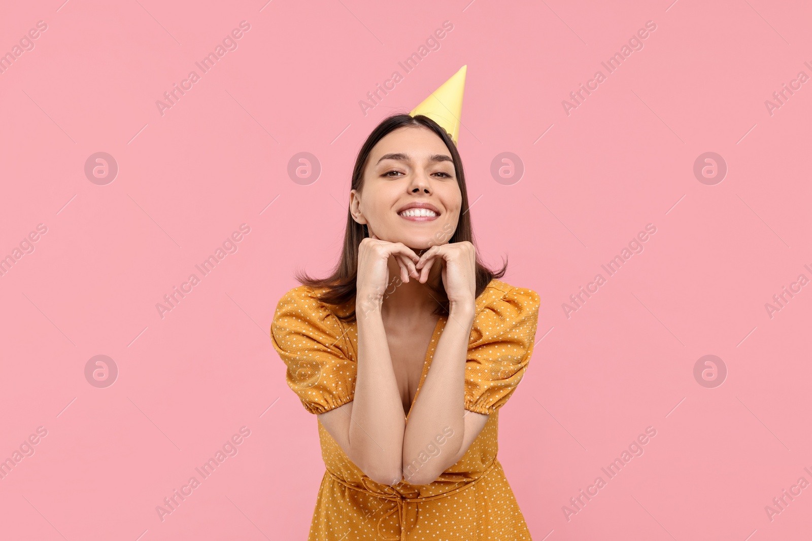 Photo of Happy young woman in party hat on pink background