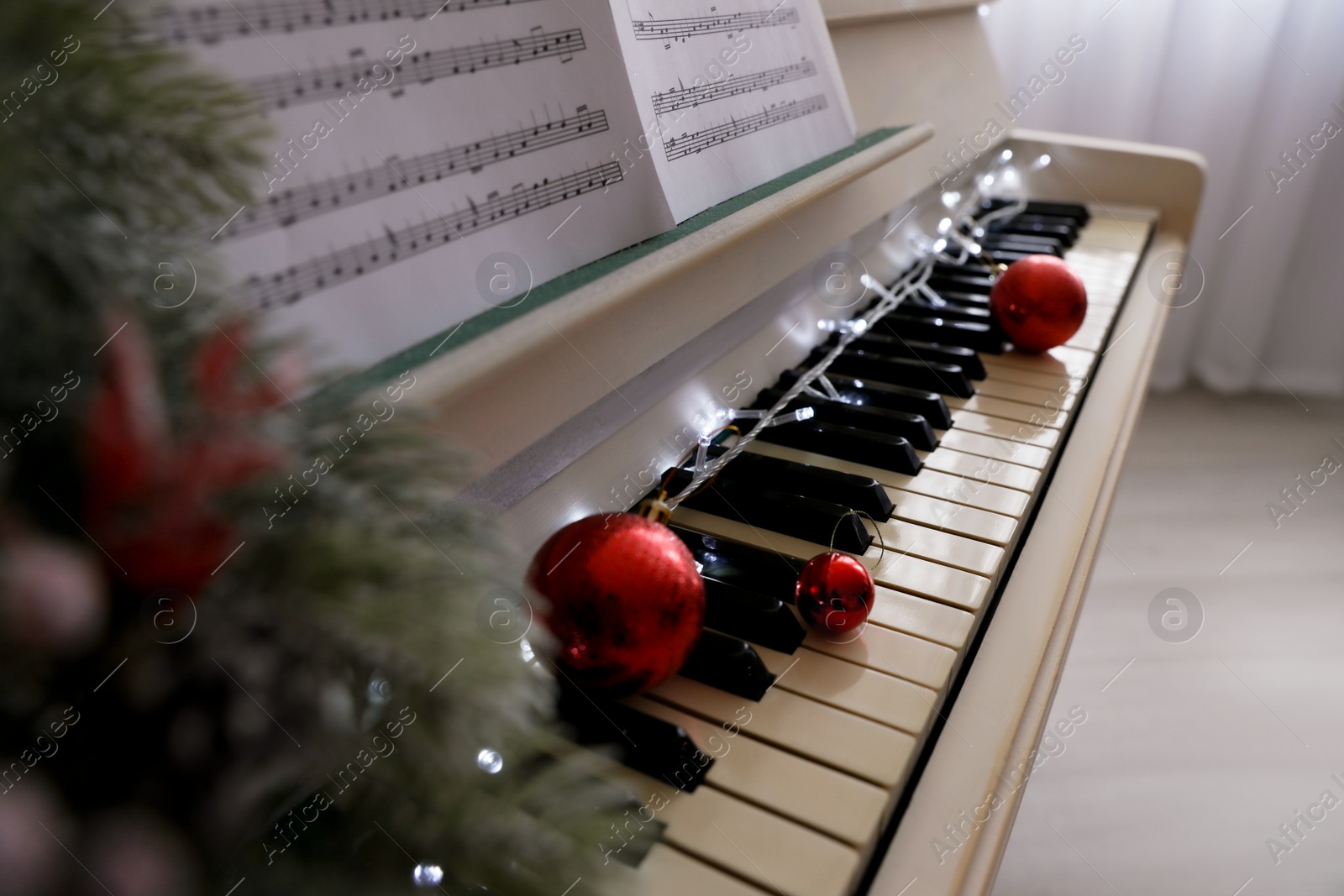 Photo of White grand piano with festive decor indoors, closeup. Christmas music