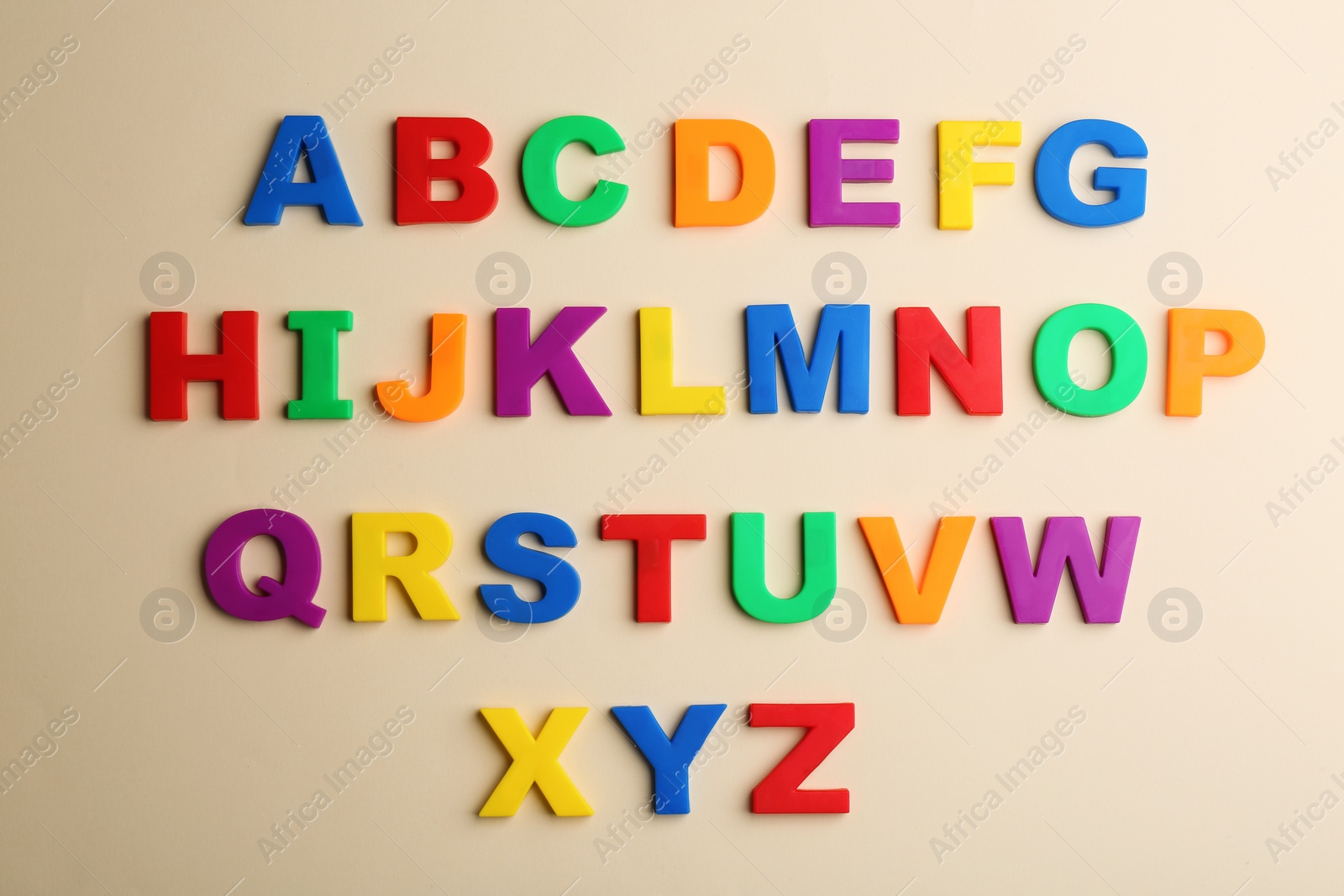 Photo of Colorful magnetic letters on beige background, flat lay. Alphabetical order