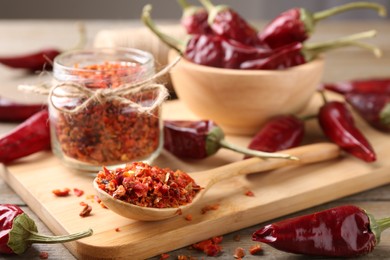 Photo of Chili pepper flakes and pods on wooden table, closeup