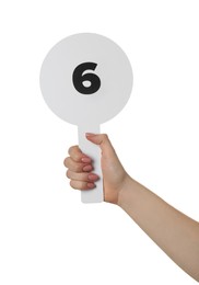 Woman holding auction paddle with number 6 on white background, closeup