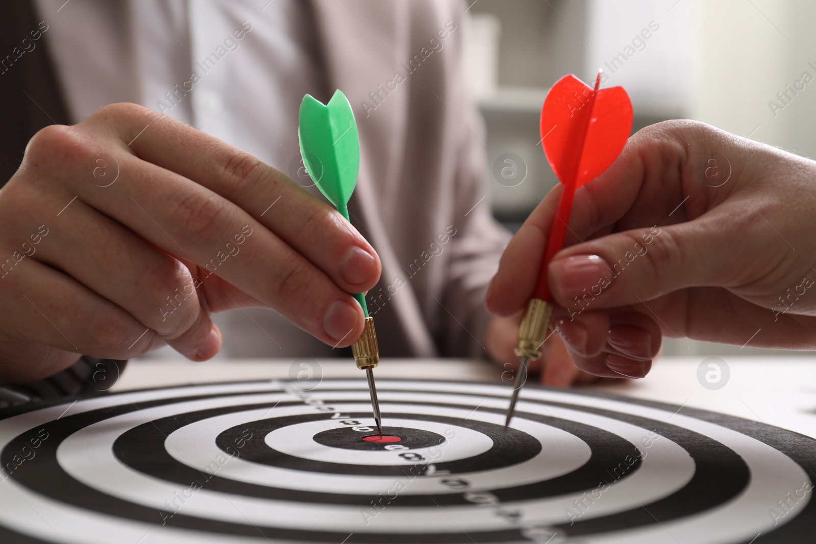 Photo of Business targeting concept. Man and woman with darts aiming at dartboard at table, closeup