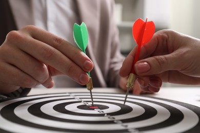 Photo of Business targeting concept. Man and woman with darts aiming at dartboard at table, closeup
