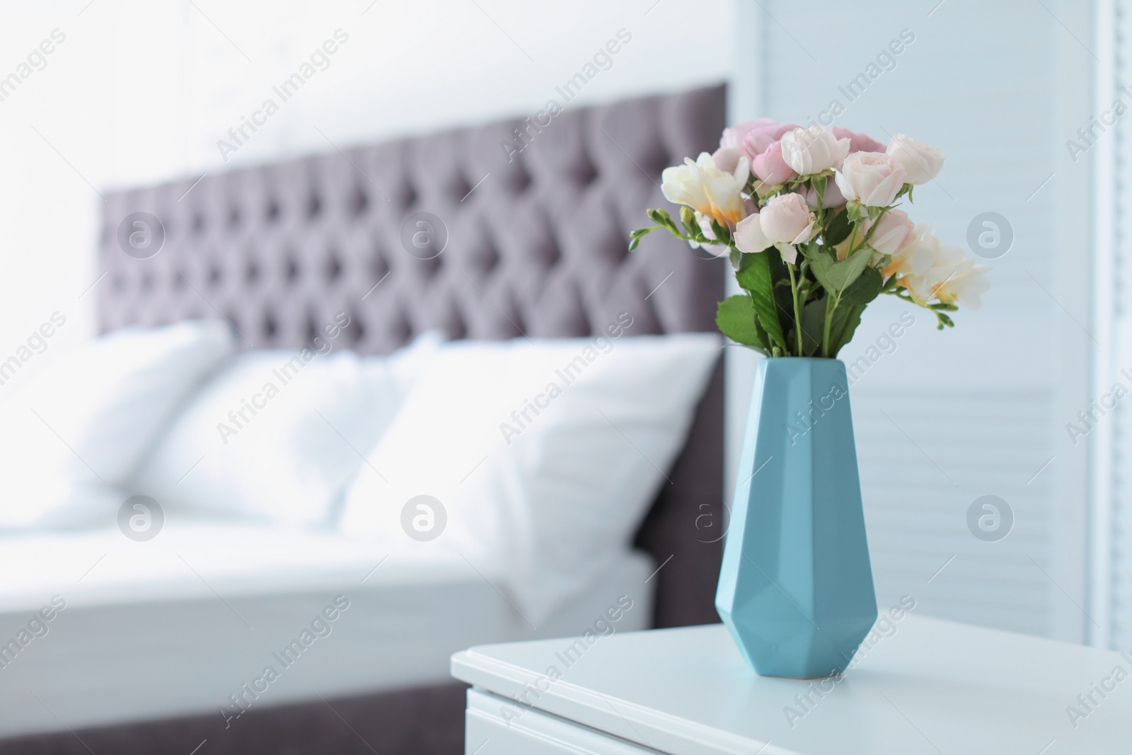 Photo of Vase with beautiful flowers on table in bedroom