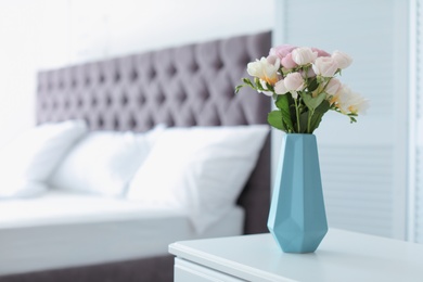 Photo of Vase with beautiful flowers on table in bedroom