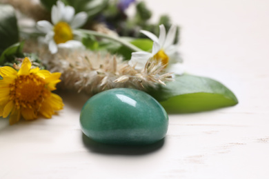 Photo of Healing gemstone and different herbs on white wooden table, closeup