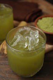 Glass of delicious iced green matcha tea on wooden table, closeup