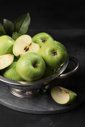 Photo of Ripe green apples with water drops and leaves on black table