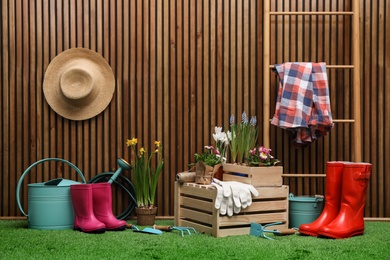 Composition with different gardening tools on artificial grass at wooden wall. Space for text