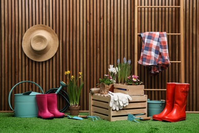 Photo of Composition with different gardening tools on artificial grass at wooden wall. Space for text