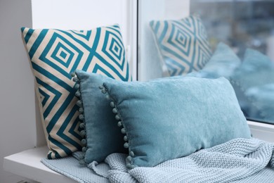 Photo of Soft pillows and blanket on window sill indoors