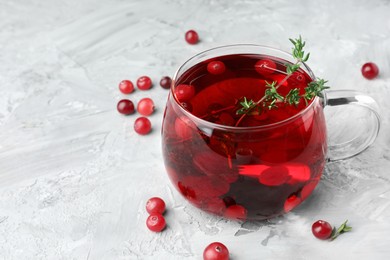 Photo of Delicious cranberry tea with thyme and berries on grey table, closeup. Space for text