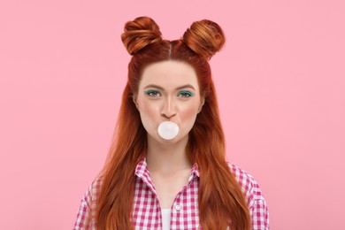 Photo of Portrait of beautiful woman with bright makeup blowing bubble gum on pink background