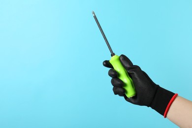 Photo of Woman holding screwdriver on light blue background, closeup. Space for text