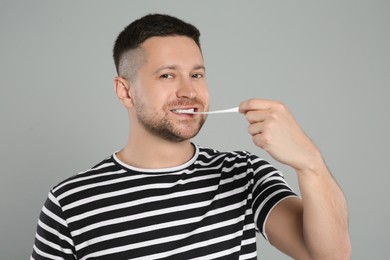 Handsome man chewing bubble gum on light grey background