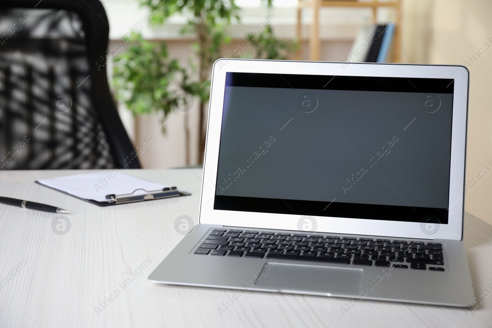 Photo of Modern laptop on white wooden table in office