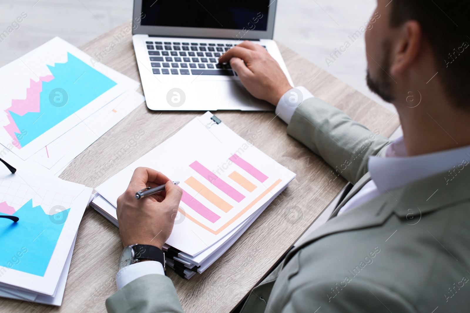 Photo of Businessman working with laptop and documents at office table