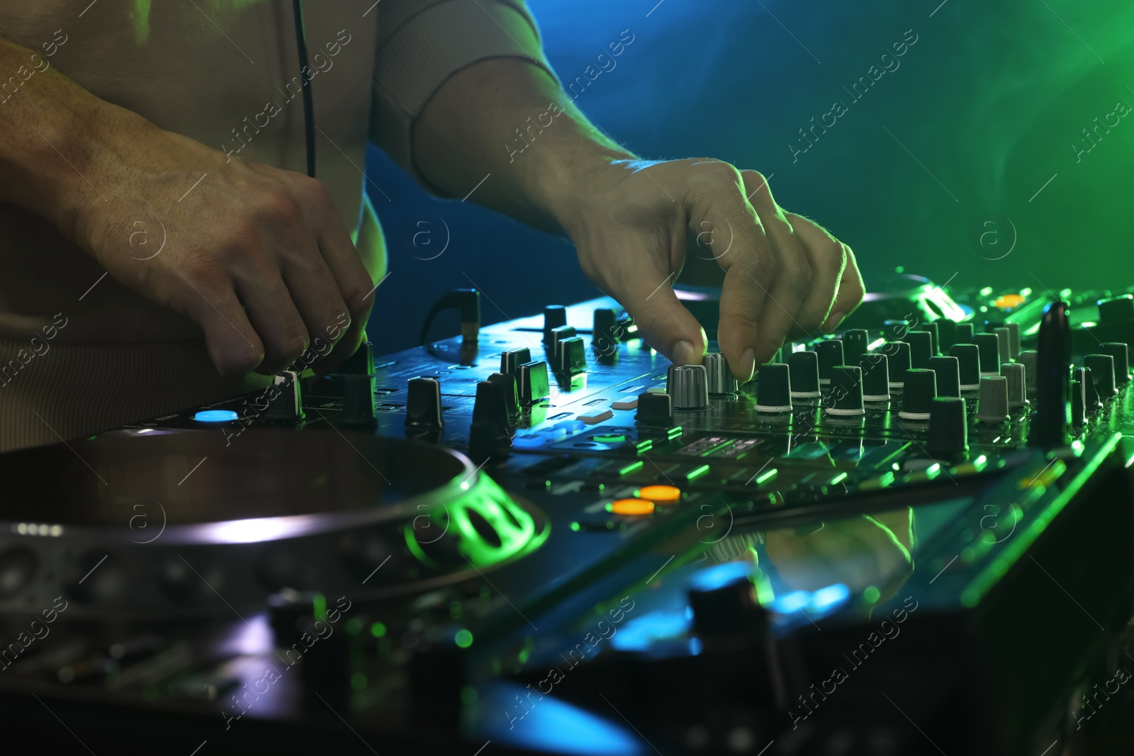 Photo of DJ creating music on modern console mixer in night club, closeup