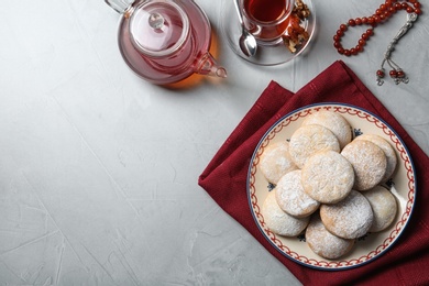 Photo of Flat lay composition with plate of traditional Islamic cookies on table, space for text. Eid Mubarak