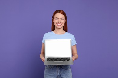 Photo of Smiling young woman showing laptop on lilac background