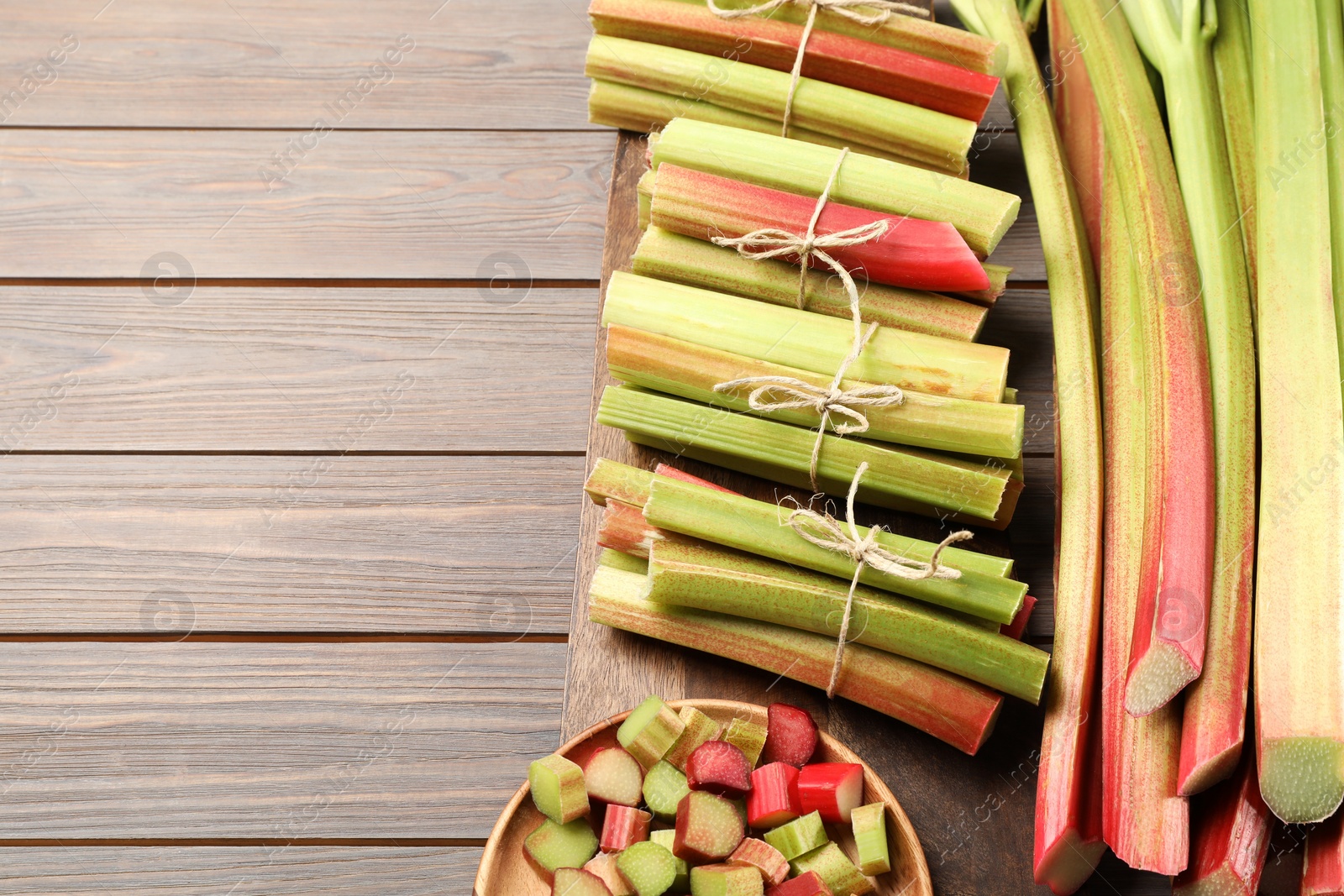 Photo of Many cut rhubarb stalks on wooden table, above view. Space for text