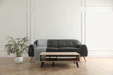 Photo of Stylish living room interior with comfortable grey sofa and wooden table