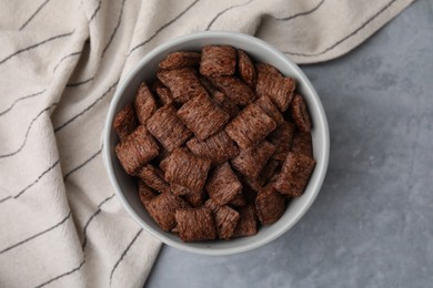 Chocolate cereal pads in bowl on grey table, top view